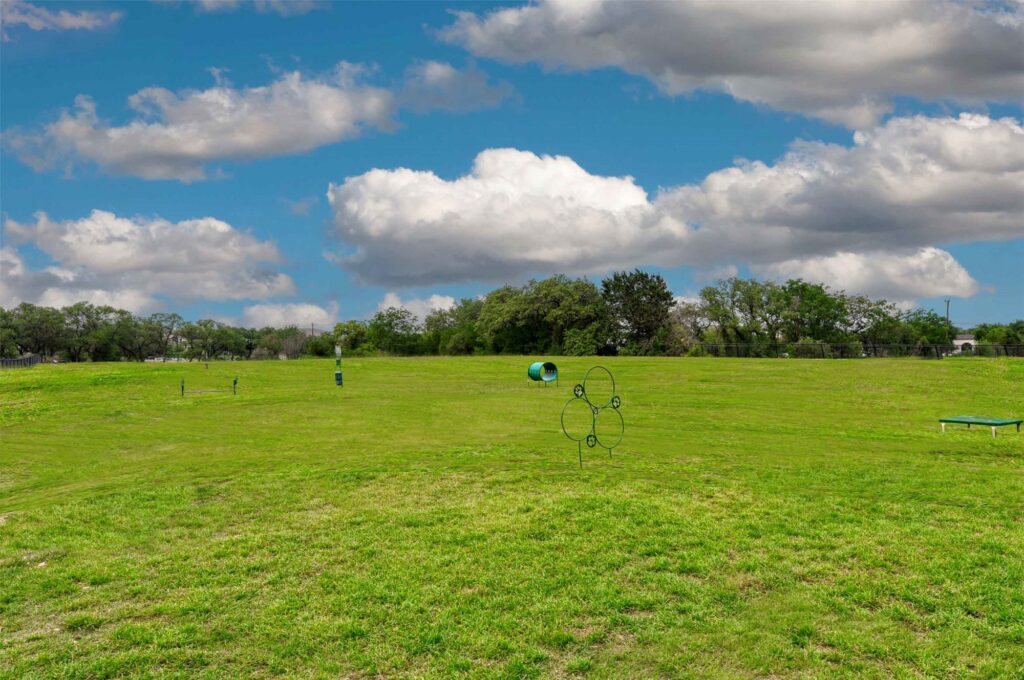 large fenced dog park with obstacles an waste station